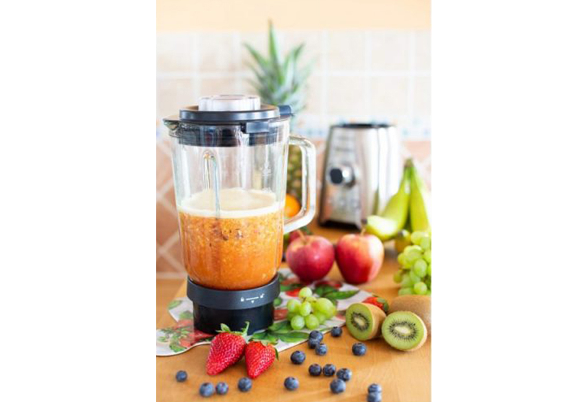 Απεικονίζεται το μπλέντερ με χυμό μέσα και γύρω του διάφορα φρούτα.